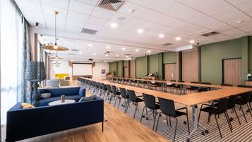 A conference room with a long table, chairs, a sofa, and a projector screen.