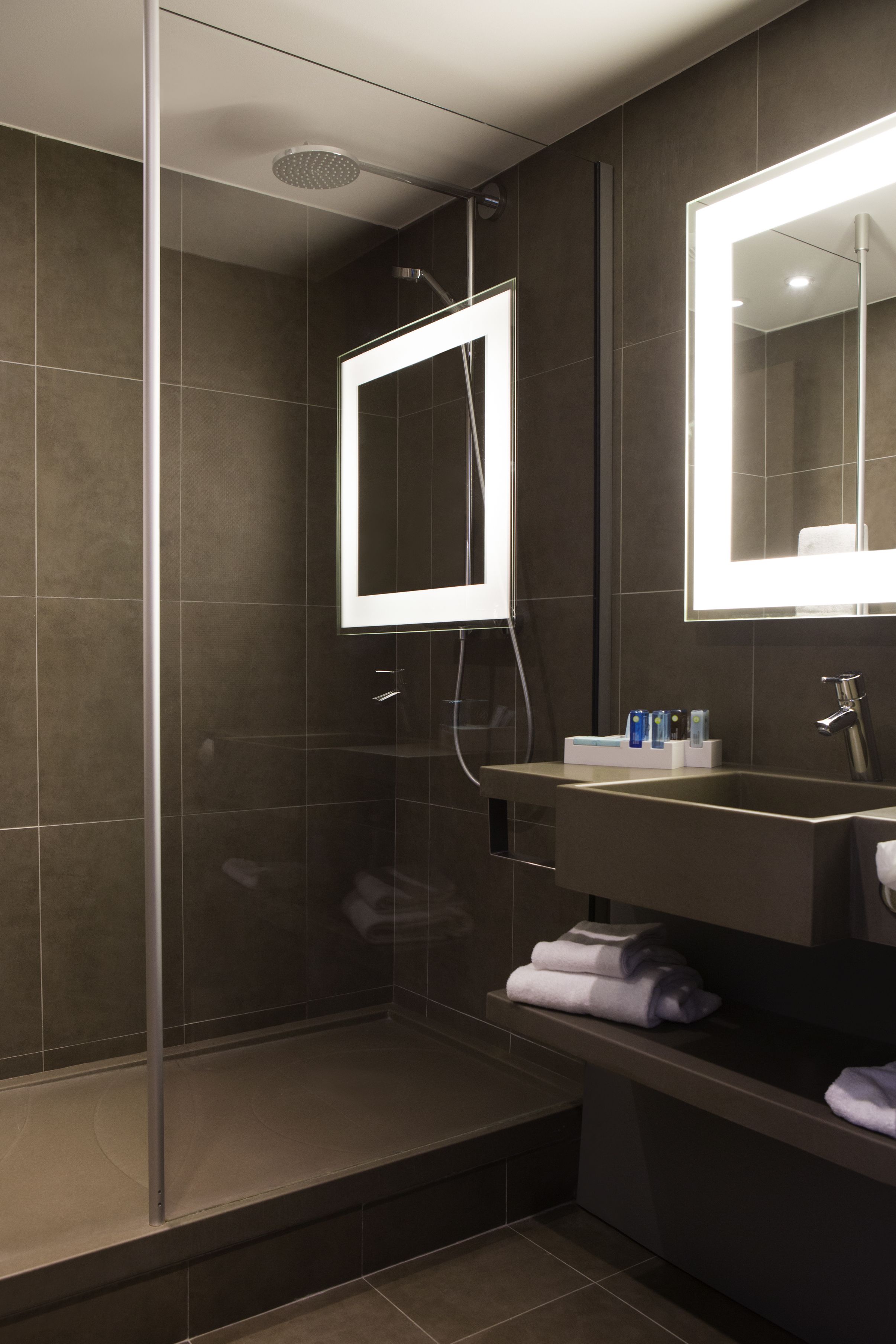 A modern bathroom with a glass-enclosed shower, a vanity with a mirror, and a towel rack.