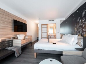 A modern bedroom with a bed, bedside table, TV, and a wall with a pattern. - Novotel Chartres (Chartres)