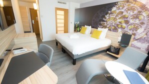 A hotel room with a bed, a desk, a chair, and a TV.