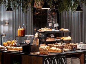 Ein reichhaltiges Frühstücksbuffet mit verschiedenen Brotsorten, Gebäck und einer Saftbar.
