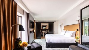 A hotel room with a large bed, a desk, a chair, a small table with a vase, and a mirror. - Sofitel Lisbon Liberdade (Lisbon)