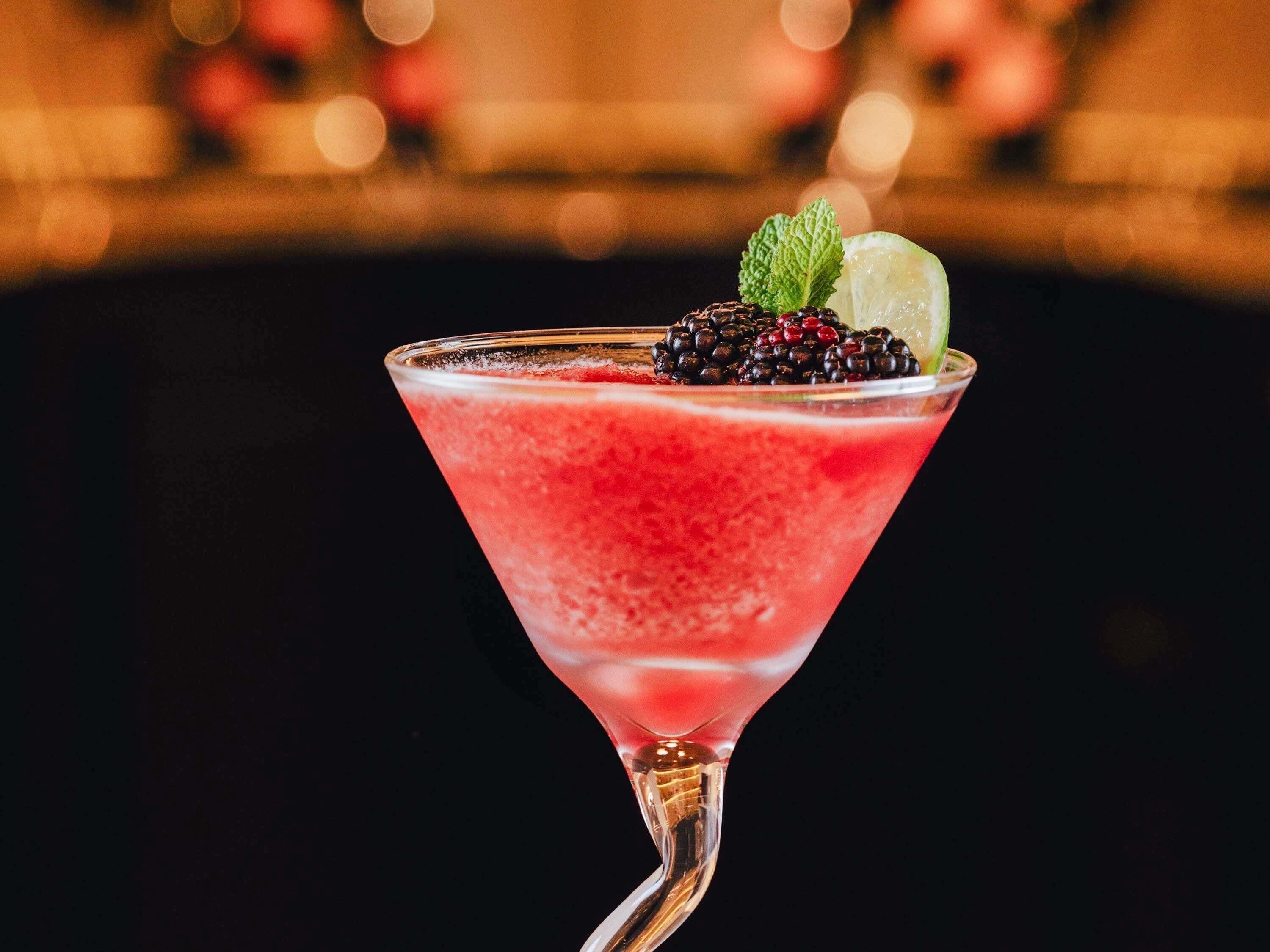 Ein Martini-Glas mit Himbeeren, Minze und Limette.