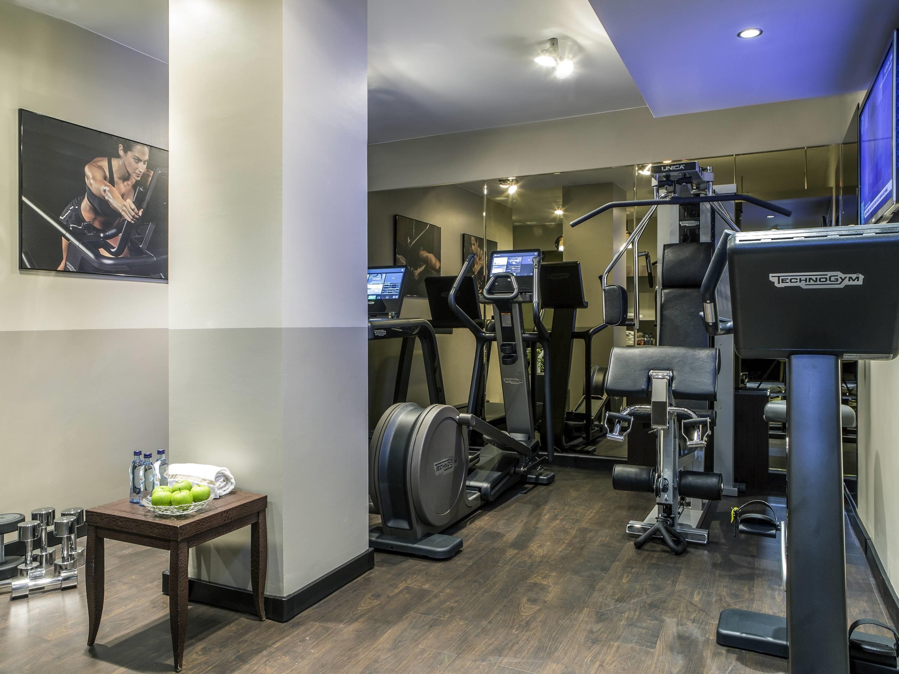 Une salle de sport équipée de machines de cardio, de matériel de musculation et dotée d’un mur entièrement recouvert de miroirs.