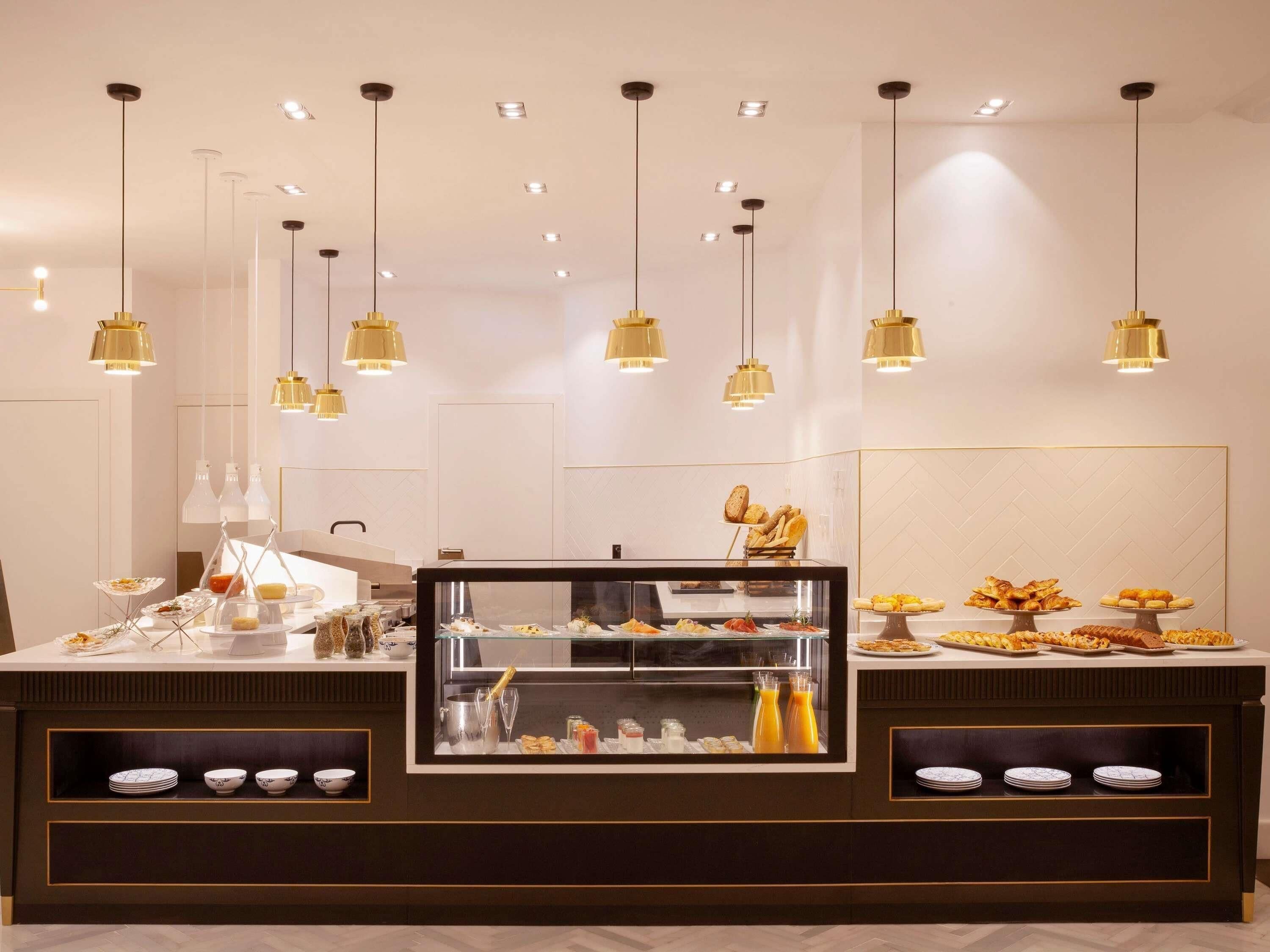 A buffet counter with multiple food displays, overhead lighting, and a glass display case.