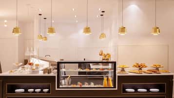 A buffet counter with multiple food displays, overhead lighting, and a glass display case.