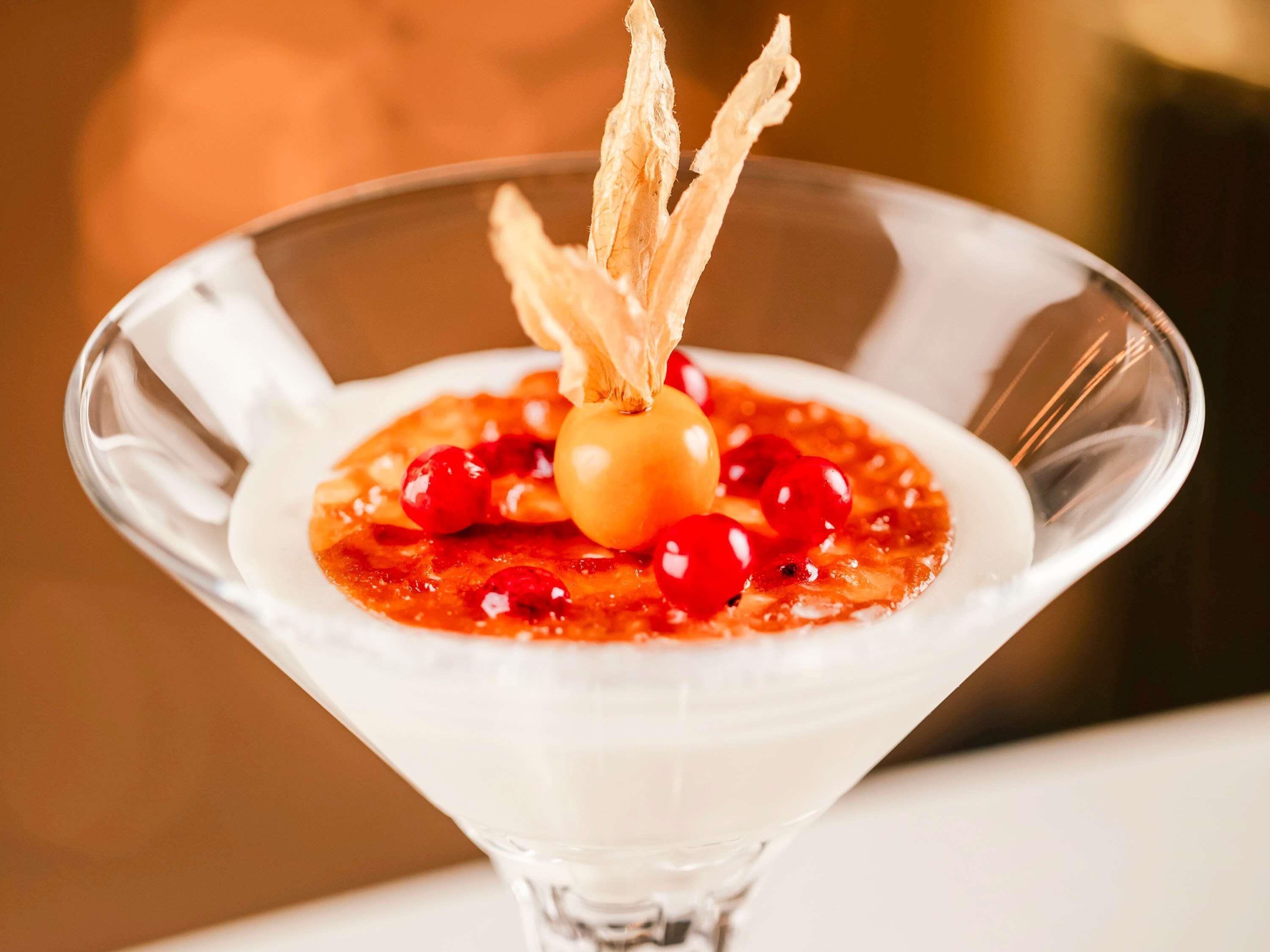 A dessert in a martini glass with a cherry and a decorative element on top.