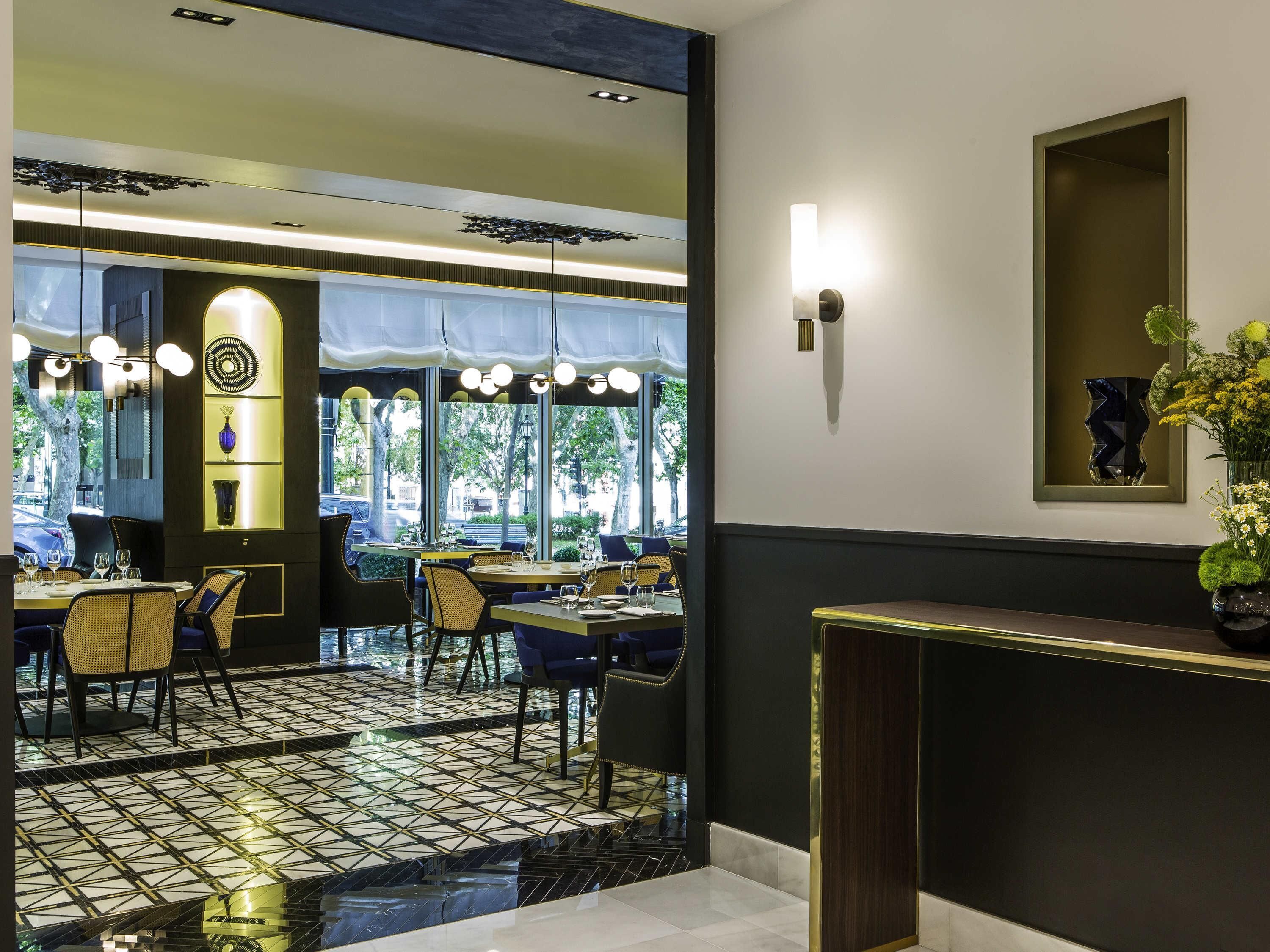 A restaurant with a modern interior, featuring a black and white tiled floor, round tables, and chairs.