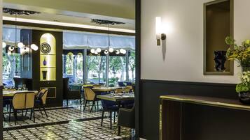 A restaurant with a modern interior, featuring a black and white tiled floor, round tables, and chairs.
