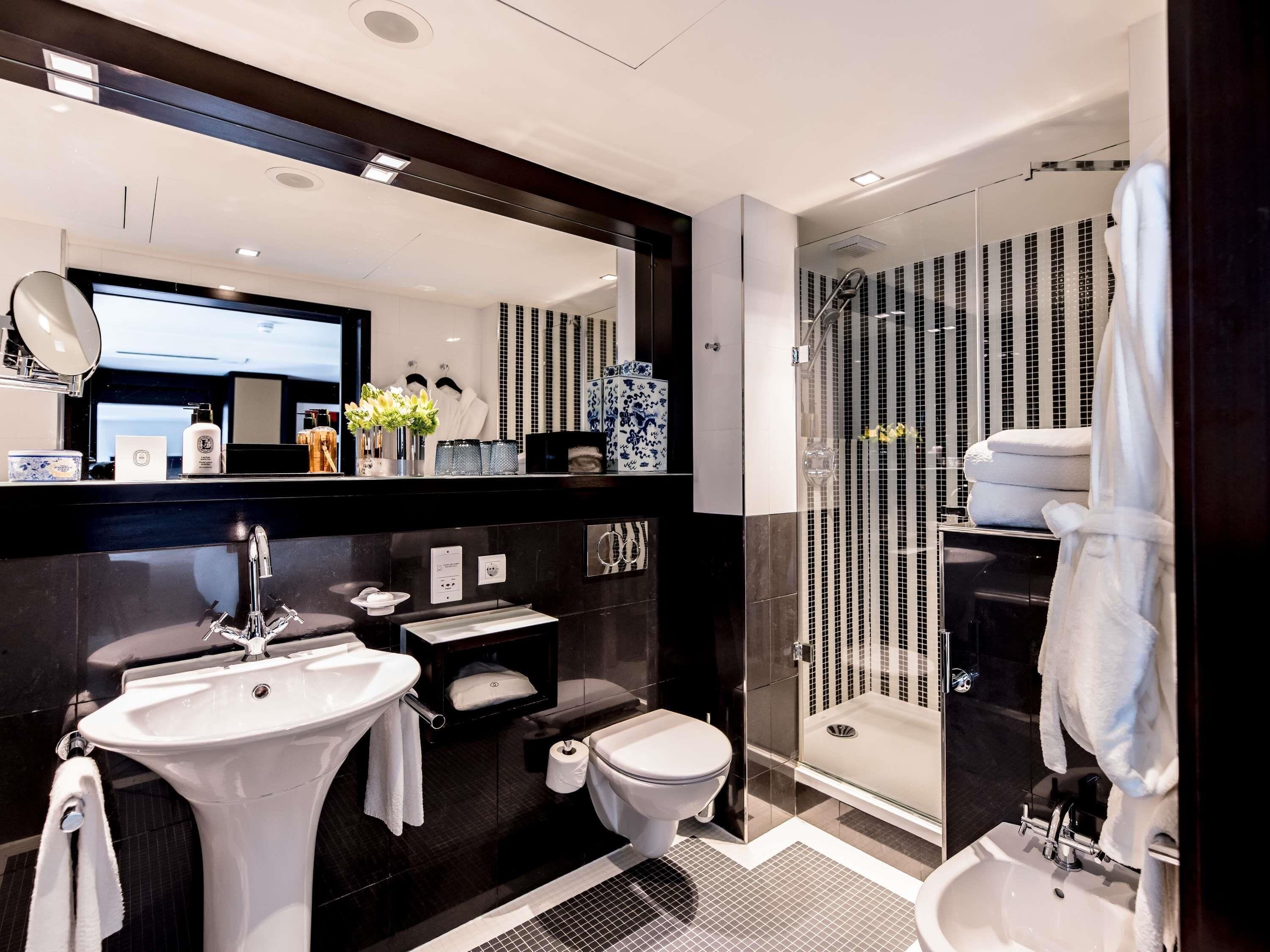 A modern bathroom with a large mirror, a sink, a toilet, and a glass-enclosed shower.