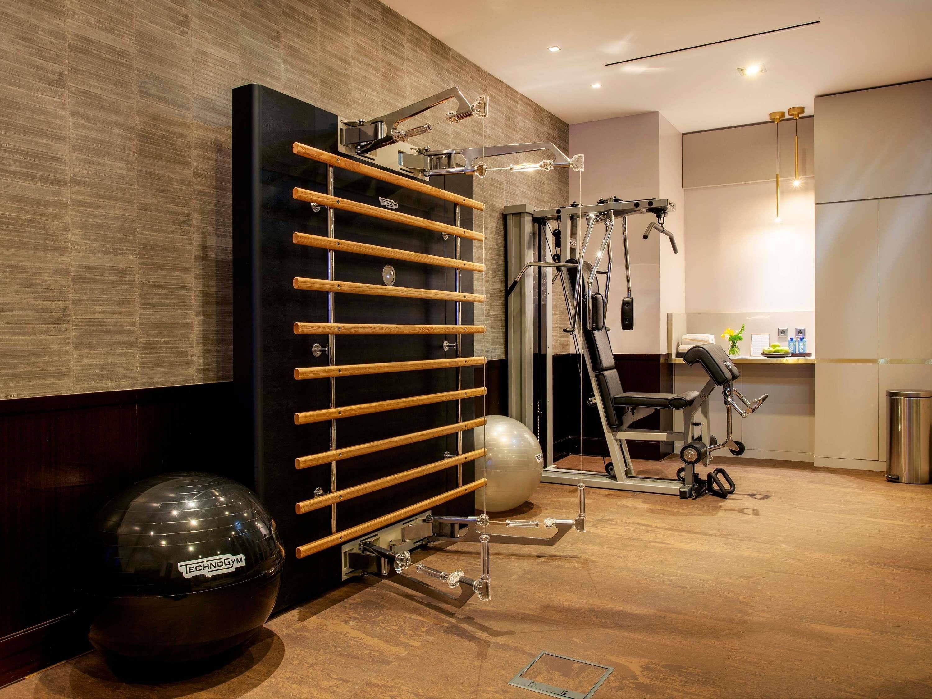 Un gimnasio con equipo de ejercicio, una pared negra con listones de madera y un espejo.