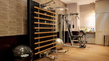 Un gimnasio con equipo de ejercicio, una pared negra con listones de madera y un espejo.