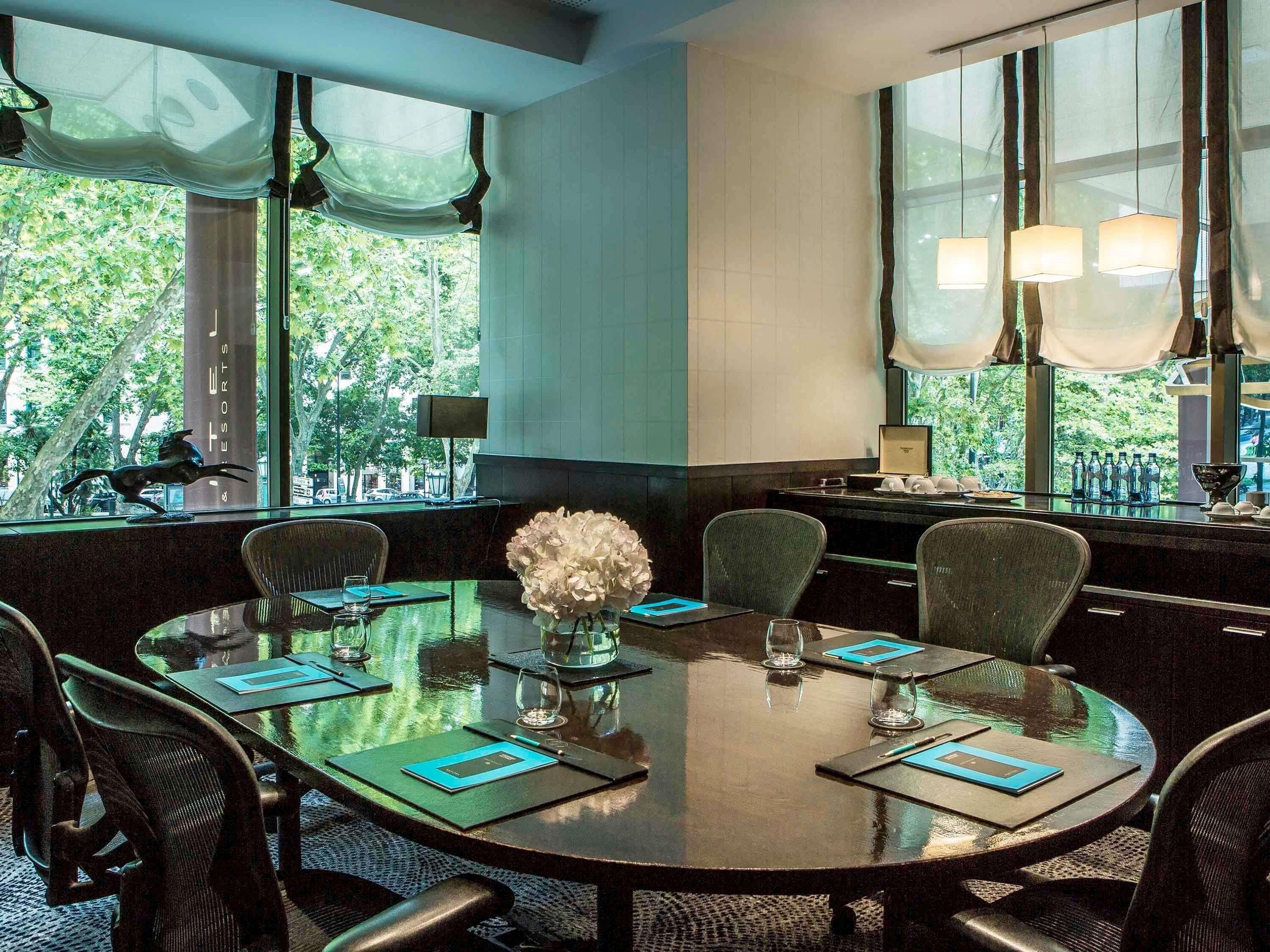 A conference room with a round table, chairs, and a vase of flowers.
