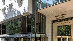 A modern building with large windows, a covered outdoor seating area, and a prominent entrance labeled 'SOFITEL.' - Sofitel Lisbon Liberdade (Lisbon)