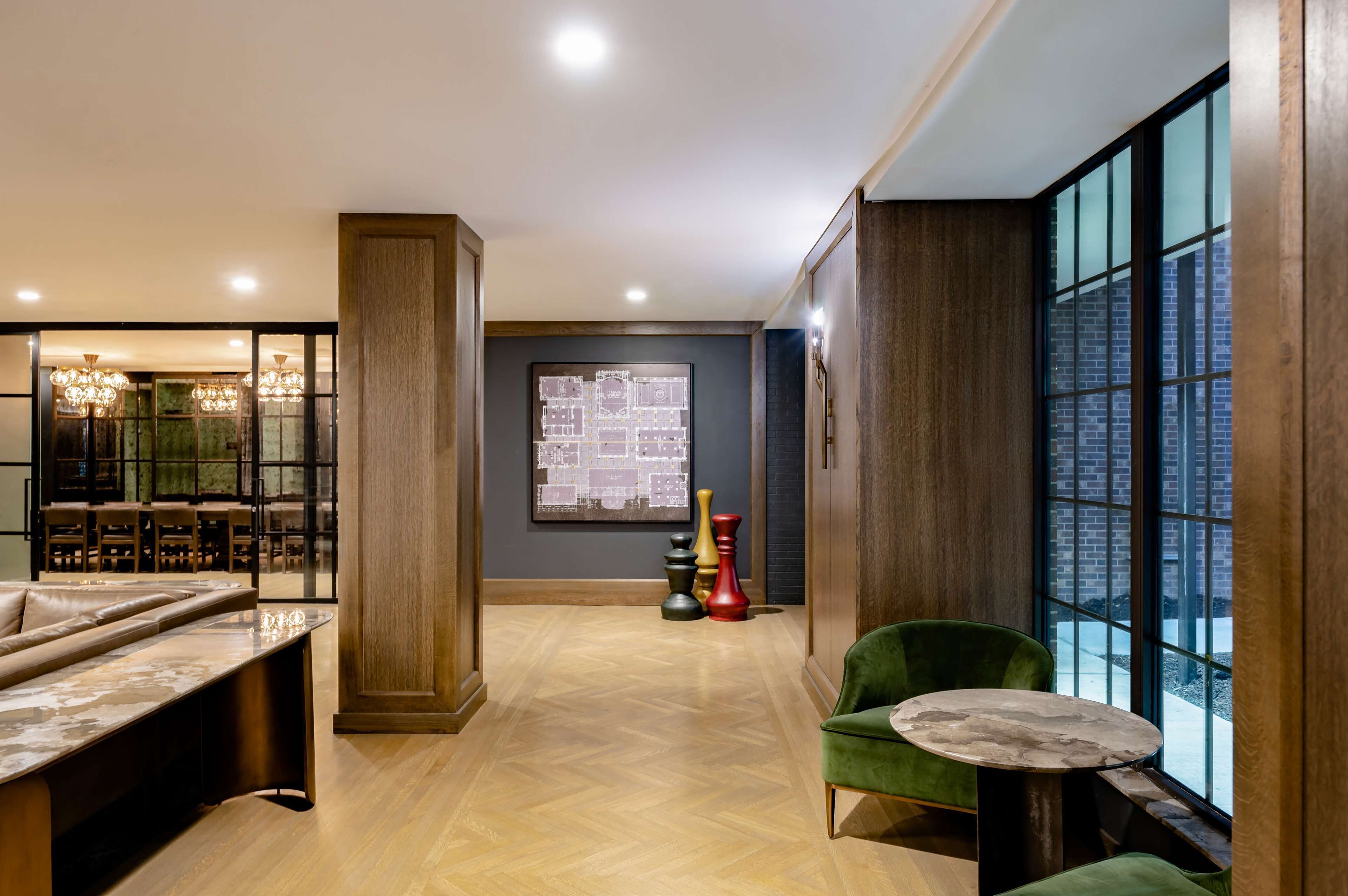A modern lobby with a seating area, a large window, and a chandelier.