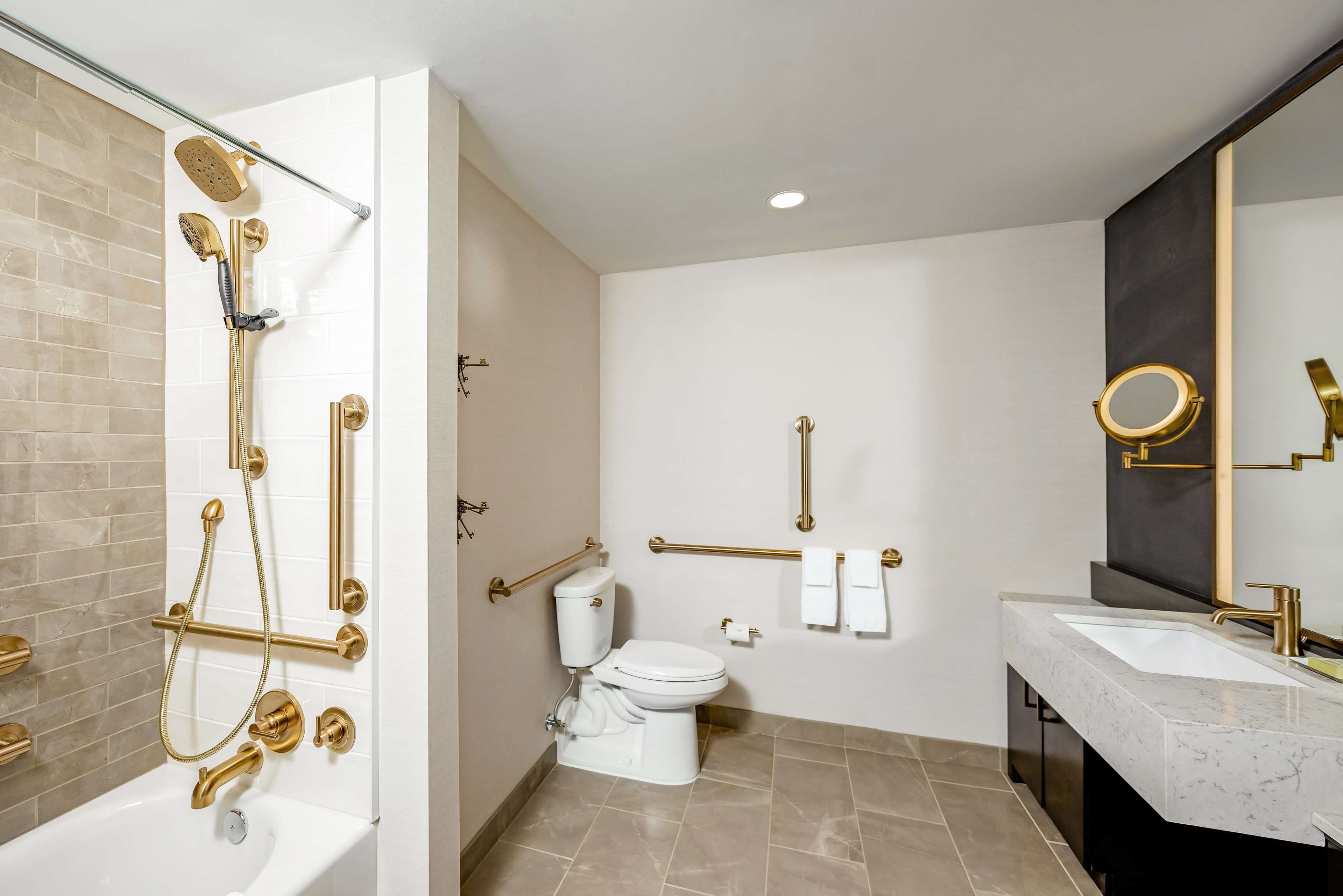 A modern bathroom with a bathtub, shower, toilet, and vanity.