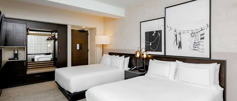 Une chambre d’hôtel avec deux lits, un bureau, une armoire et des œuvres d’art accrochées au mur.