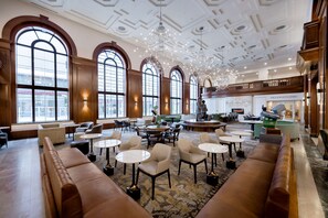A spacious lobby with high ceilings, large arched windows, and a variety of seating arrangements including sofas and tables. - Hotel Fort Des Moines, Curio Collection by Hilton (Des Moines)