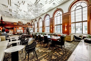 A spacious lobby with high ceilings, large windows, and a chandelier. - Hotel Fort Des Moines, Curio Collection by Hilton (Des Moines)