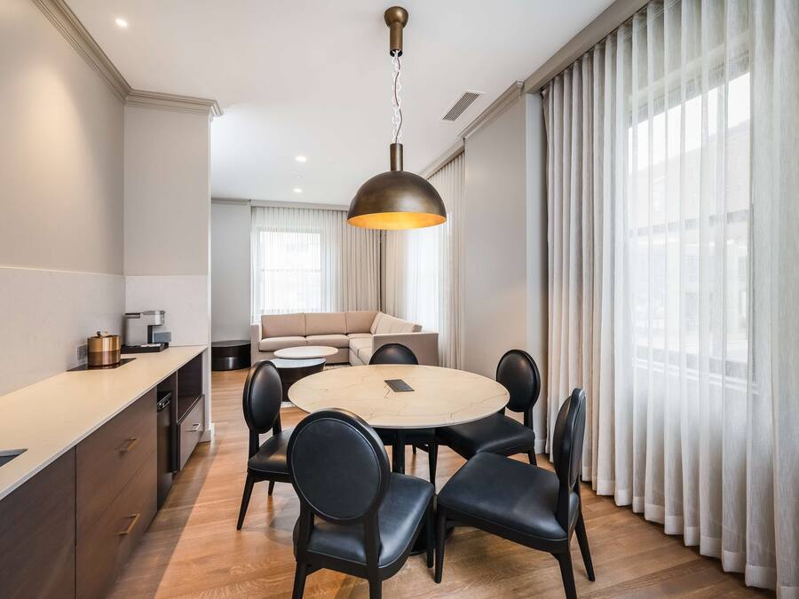A modern dining area with a round table, black chairs, and a pendant light.