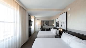 A hotel room with two beds, a desk, and a chair.