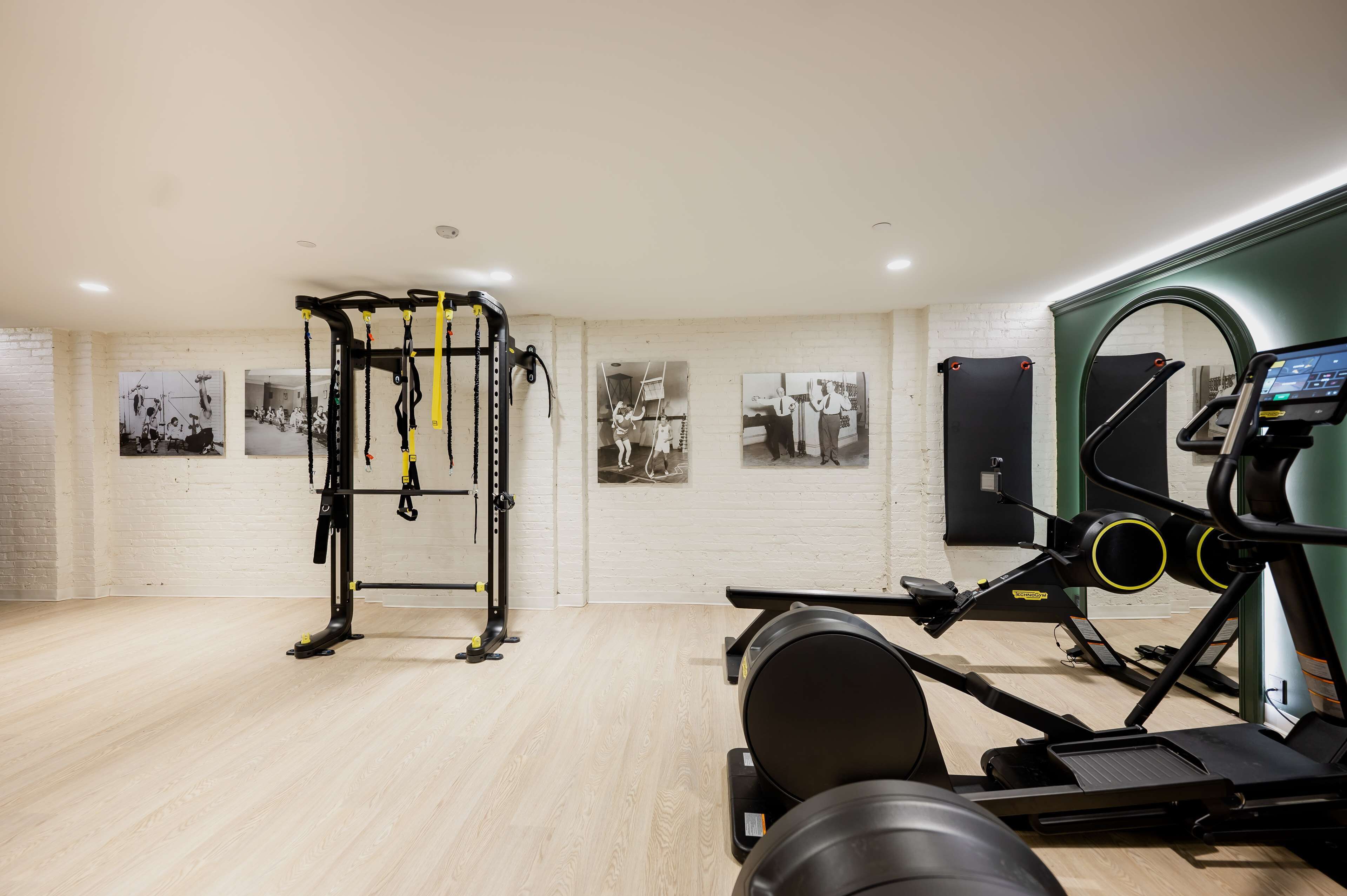 A gym with exercise equipment, including a TRX suspension trainer and cardio machines.