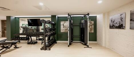 Ein Fitnessstudio mit Krafttrainingsgeräten, Kurzhanteln und Trainingsmaschinen.