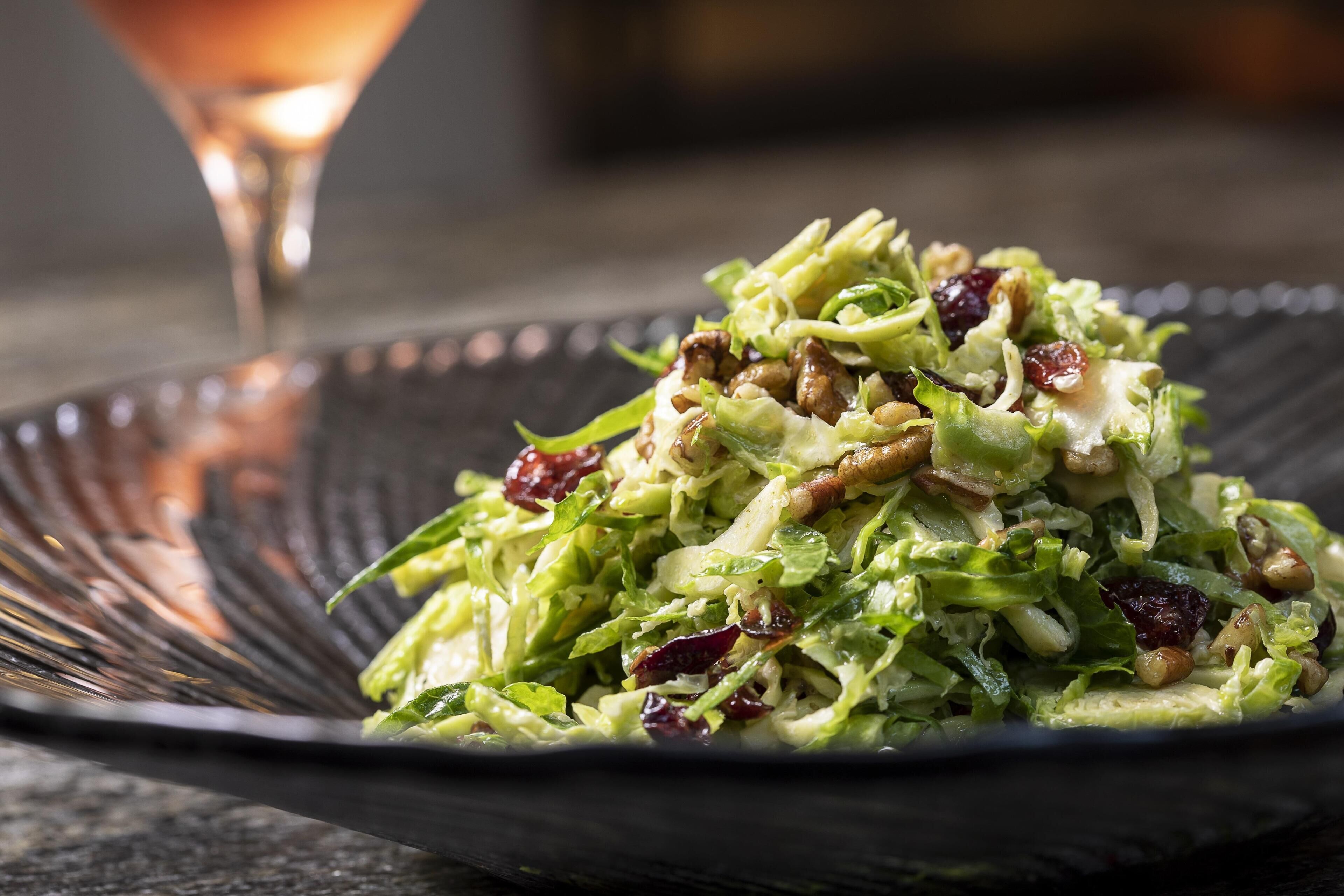 Un'insalata con noci e frutta secca su un piatto scuro.