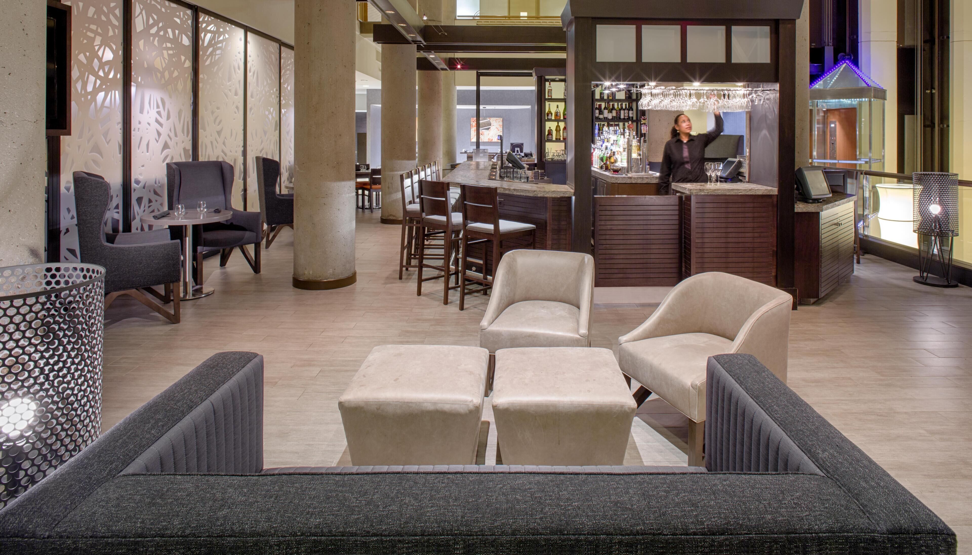 Un hall d’hôtel comprenant des espaces de détente, un bar et un comptoir d’accueil.