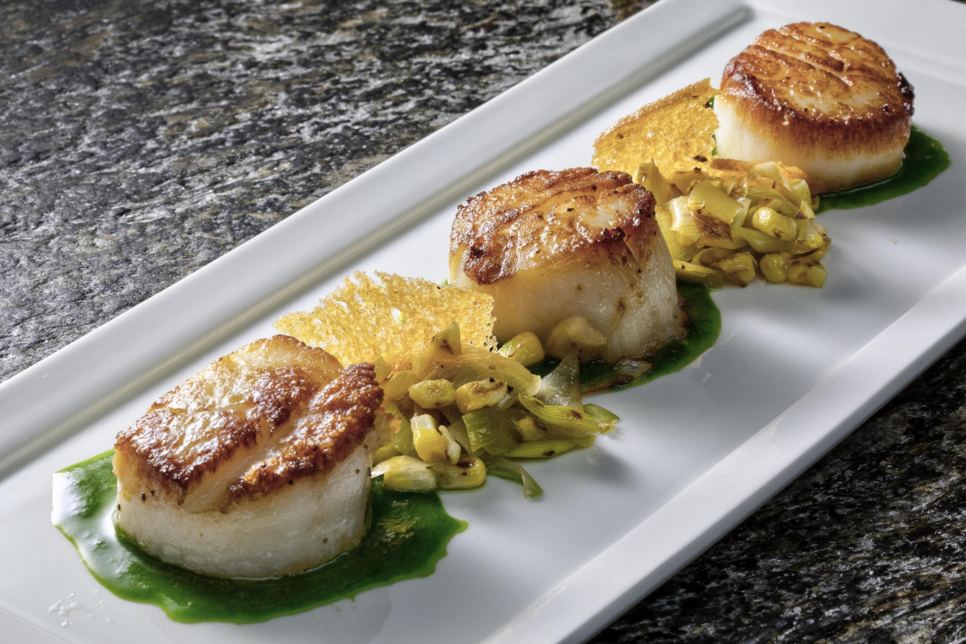 A plate of food with scallops and vegetables.