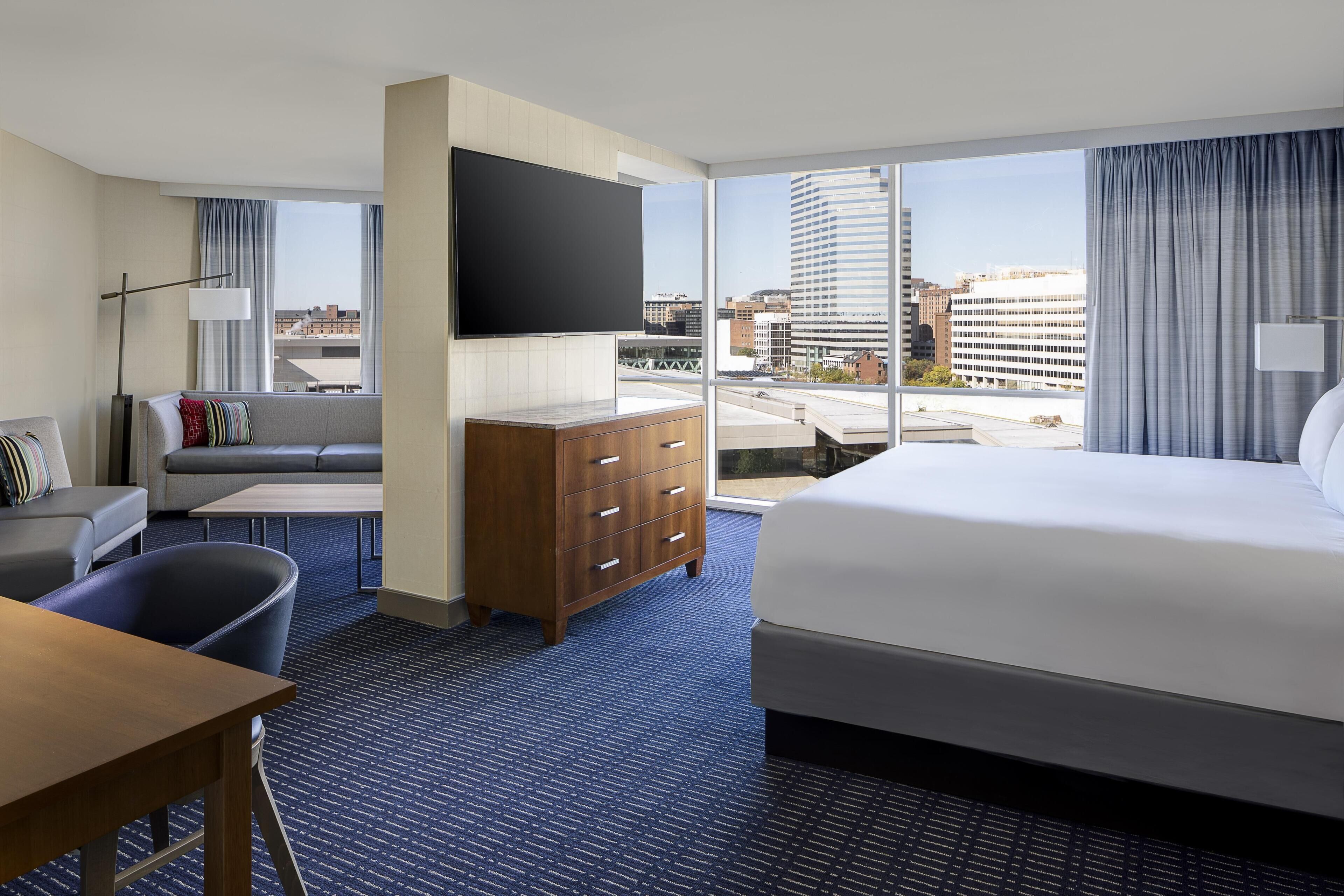 Une chambre d’hôtel avec un grand lit, un canapé, un bureau, une commode et un téléviseur.