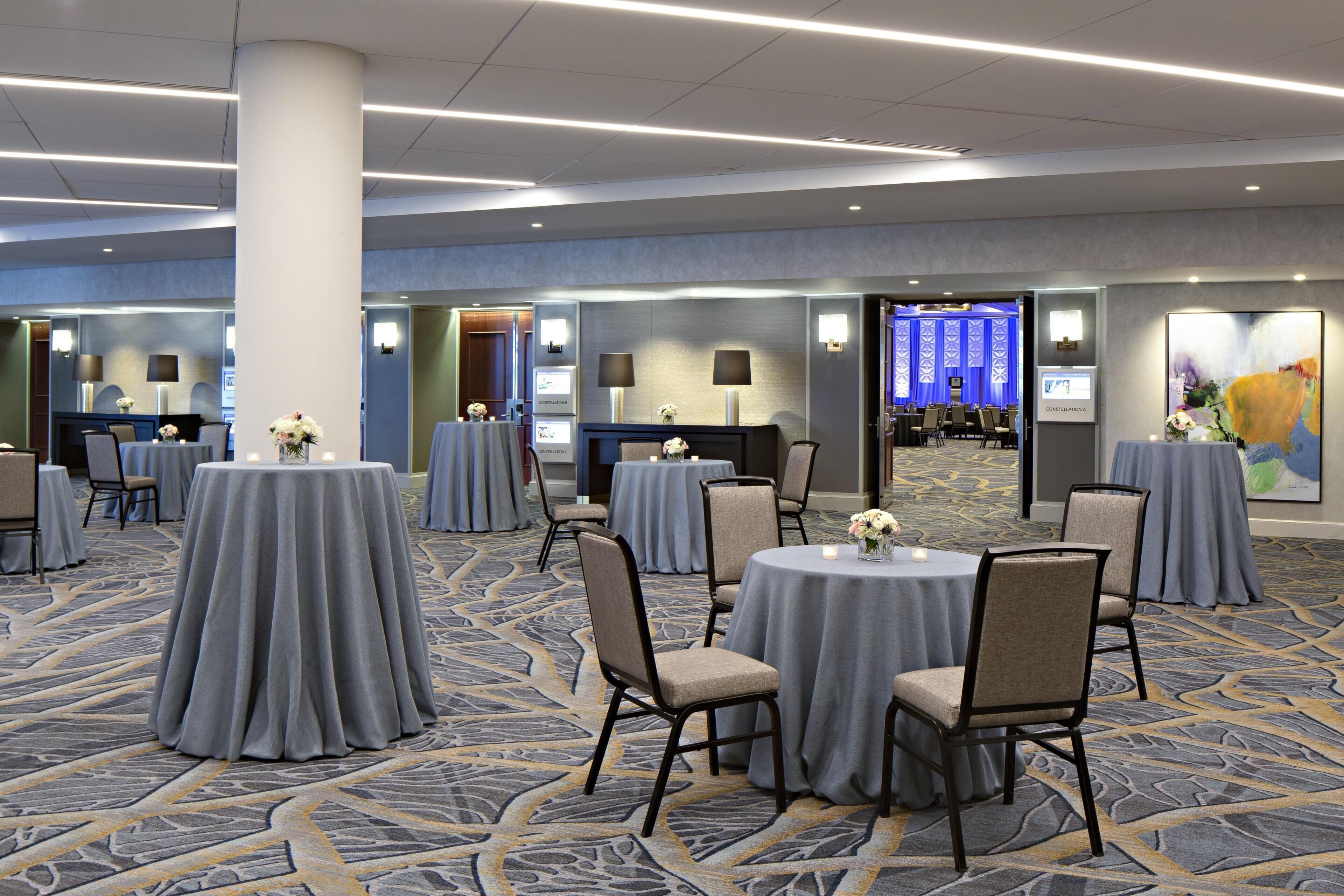 A conference room with round tables, chairs, and a carpeted floor.