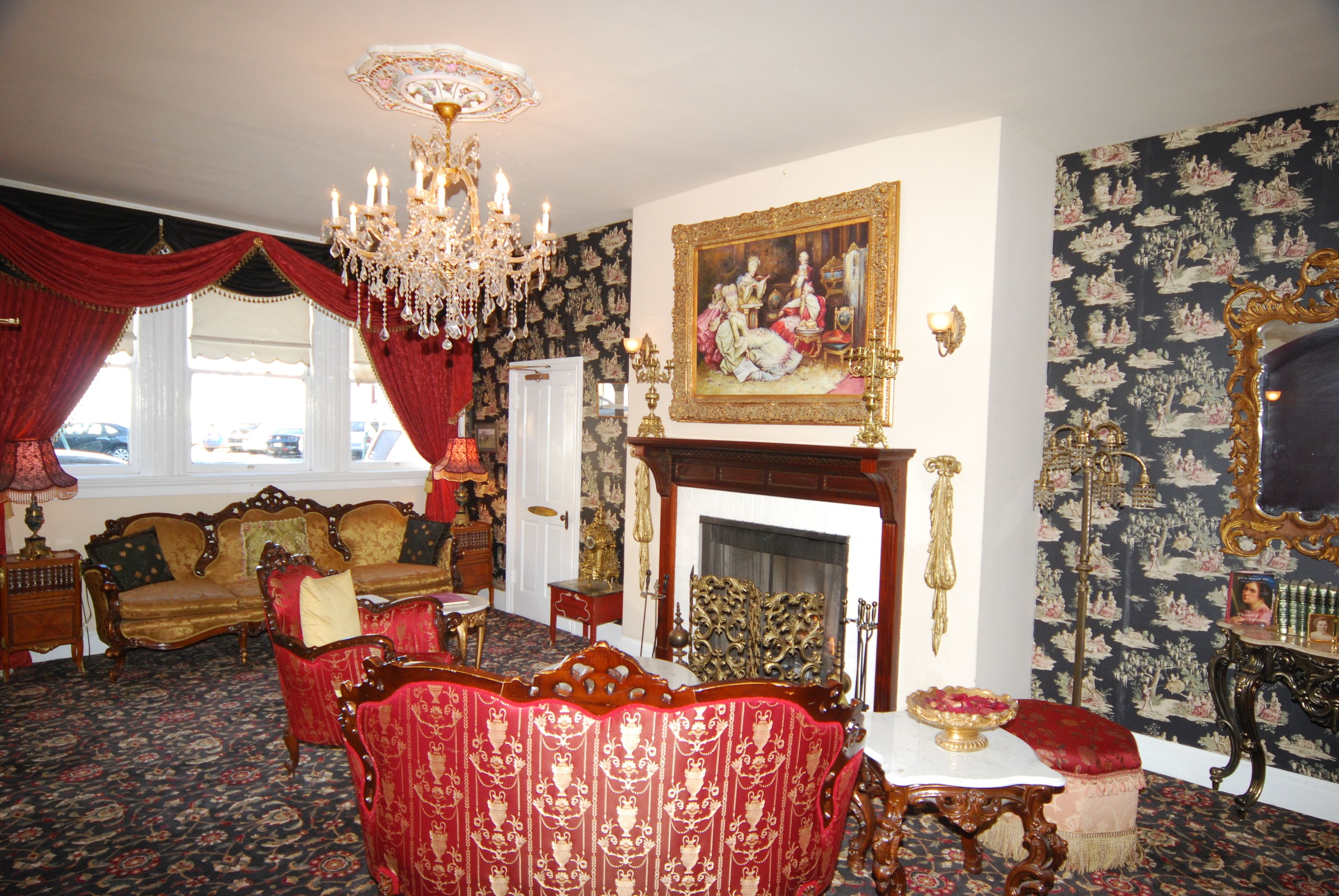 A room with a chandelier, a fireplace, a sofa, and a patterned wallpaper.
