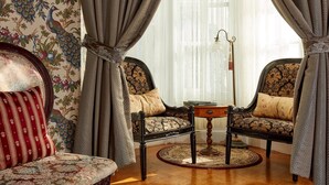 A room with two upholstered chairs, a small table, and a patterned rug. - Queen Anne Hotel (San Francisco)