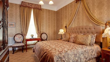 A bedroom with a large bed, a dresser, a vanity, and a chandelier.