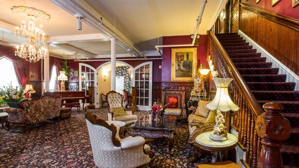 A grand room with a staircase, ornate furniture, and a chandelier. - Queen Anne Hotel (San Francisco)