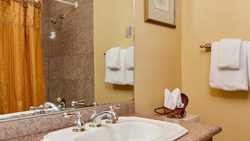 A bathroom with a granite countertop, a white sink, a wooden vanity, a toilet, a towel rack, and a framed picture on the wall.