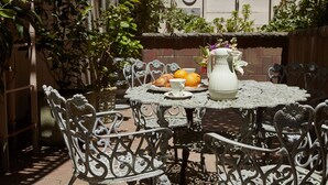 An outdoor patio with a round table, chairs, and a pitcher of water. - Queen Anne Hotel (San Francisco)