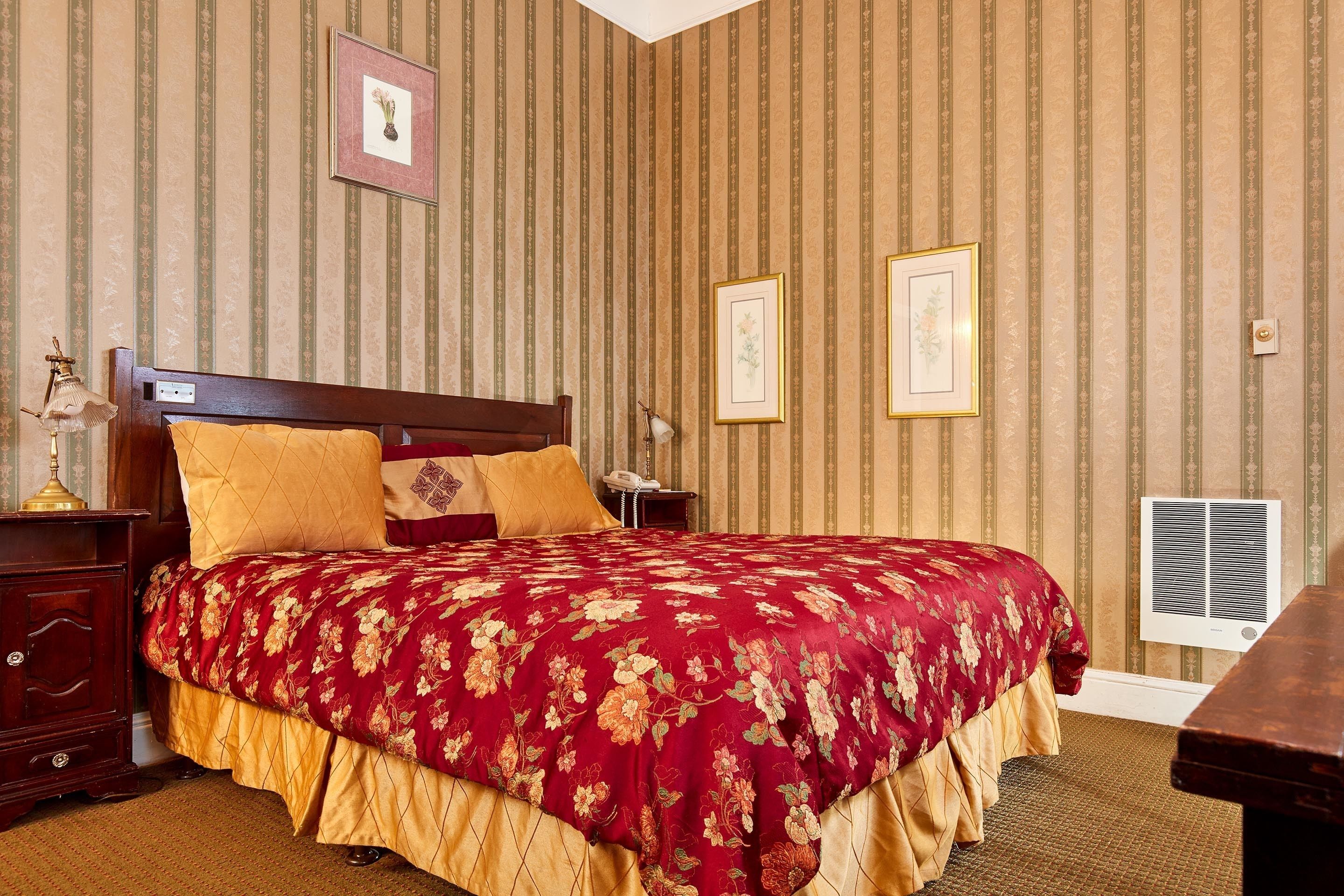 Ein Hotelzimmer mit einem großen Bett, einem Nachttisch und einer Wand-Klimaanlage.