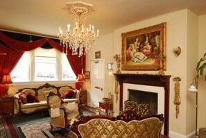 A traditional room with a fireplace, ornate furniture, and a chandelier. - Queen Anne Hotel (San Francisco)