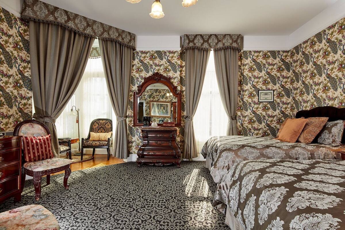 A bedroom with a large bed, a dresser, a chair, and a mirror.