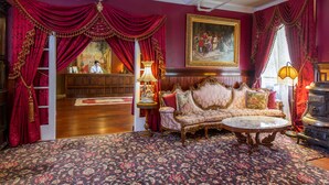 A room with a patterned carpet, a sofa, a table, and a stove. - Queen Anne Hotel (San Francisco)