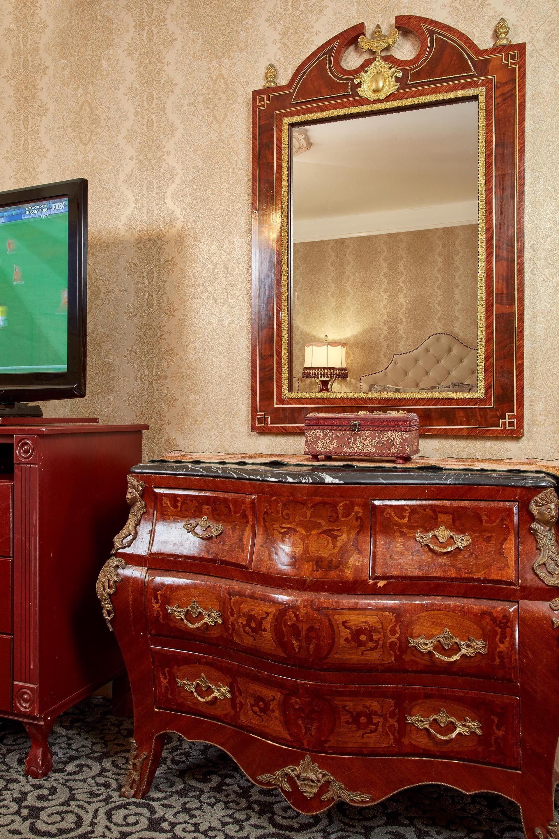 A wooden dresser with ornate carvings and a mirror above it.