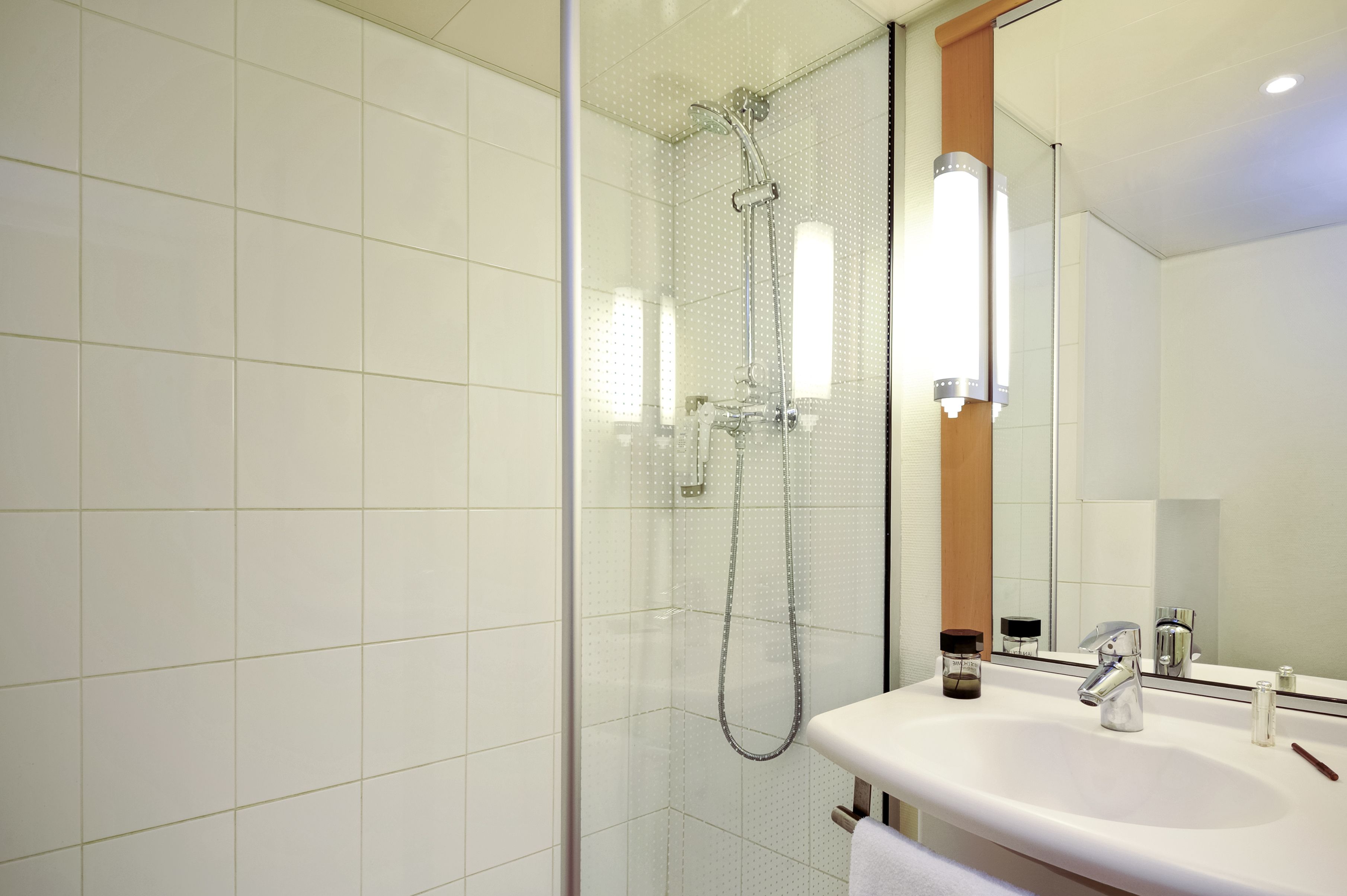 A modern bathroom with a glass-enclosed shower, a white sink, and a large mirror.