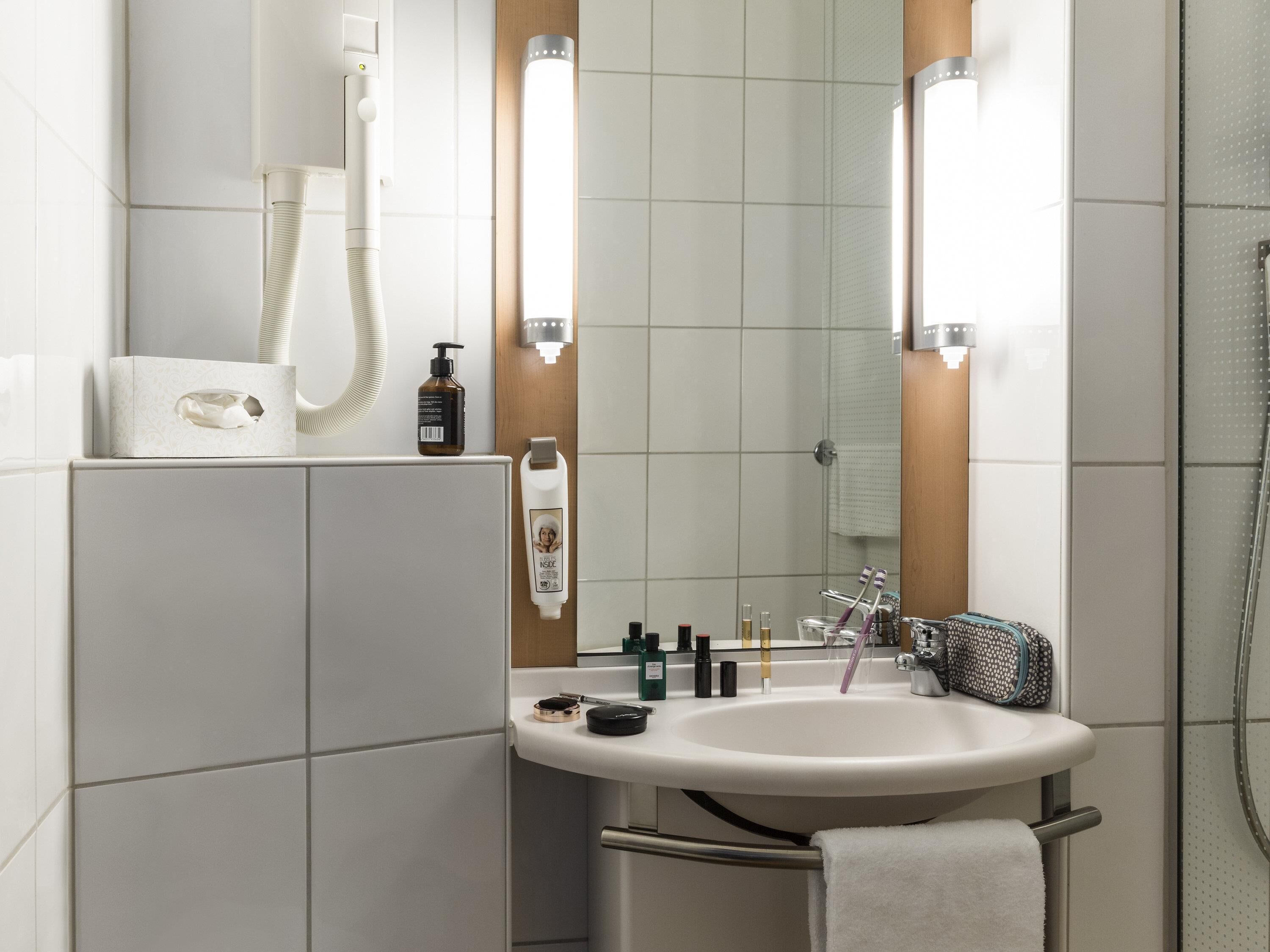 Un baño moderno con lavamanos, espejo y toallero blancos.