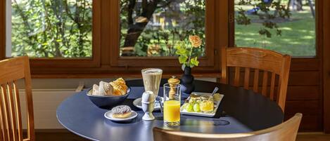 A round table with breakfast items, including croissants, a glass of orange juice, and a small vase with flowers.