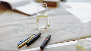 Un escritorio con un vaso de agua, un bolígrafo y una libreta.
