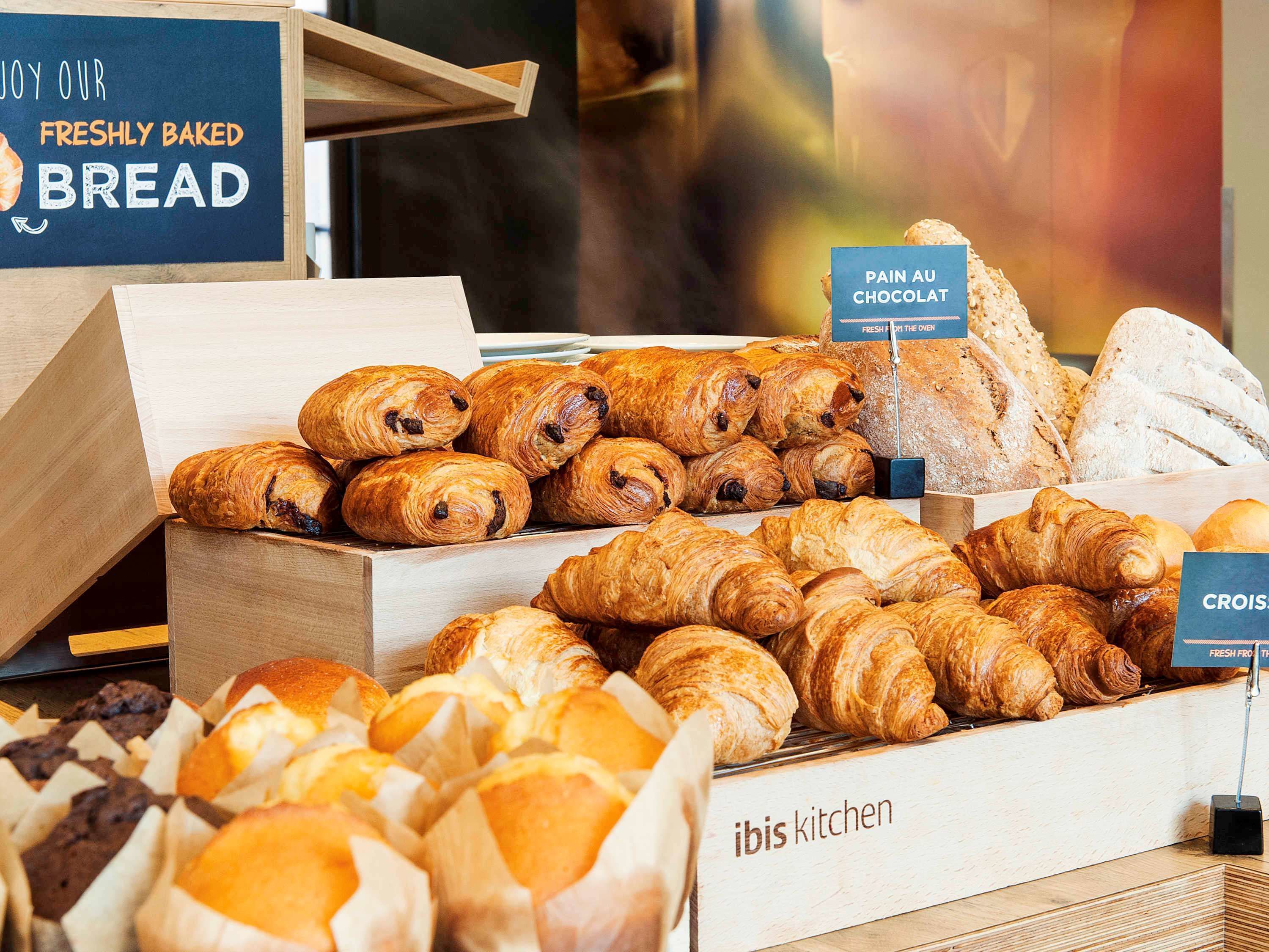 A bakery display with various types of bread and pastries, including croissants and pain au chocolat.
