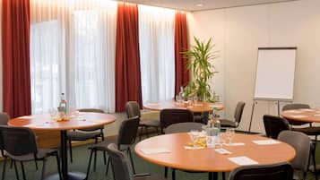 Ein Konferenzraum mit runden Tischen, Stühlen, einer Whiteboard-Tafel und einem Projektor.