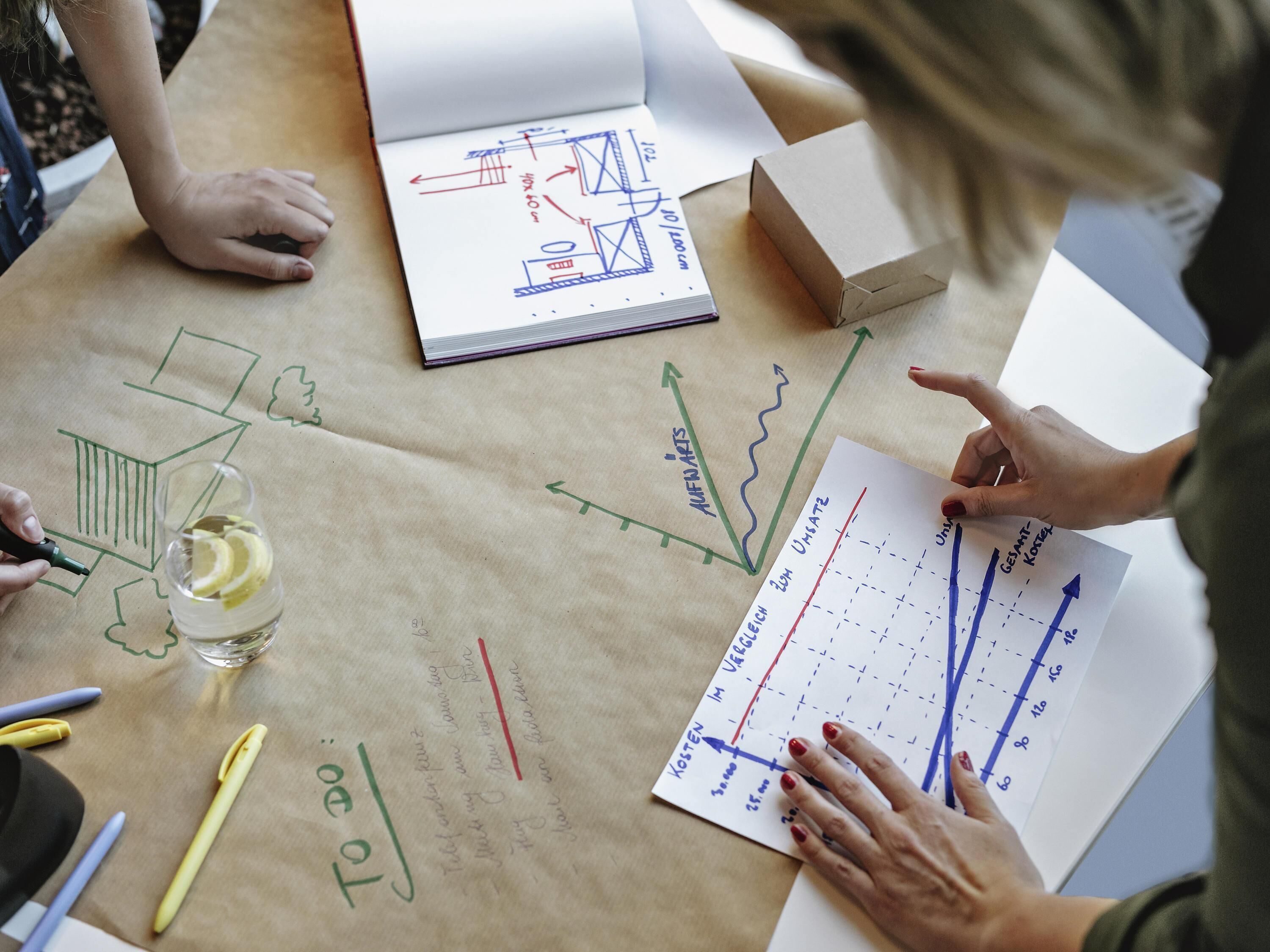 Une table avec des plans d’architecture, un carnet et un verre contenant des rondelles de citron.